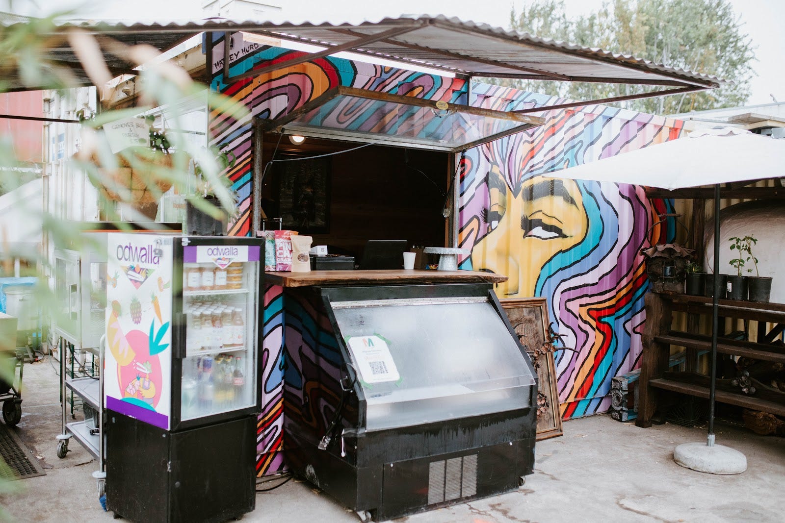 A small corrugated metal structure painted with a colorful woman’s head used as a shop.