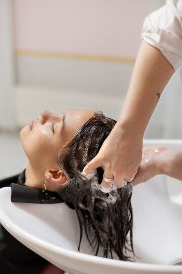 Person applying hair treatment after washing, emphasizing the improvement in hair texture and managing stress through targeted hair care products.