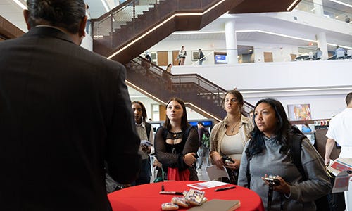 Students listen to a man at a networking event.