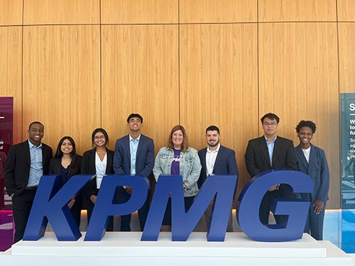Students stand behind large letters that spell "KPMG."
