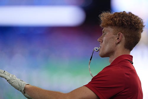 Anderson, with a whistle in his mouth, instructs the band to play.