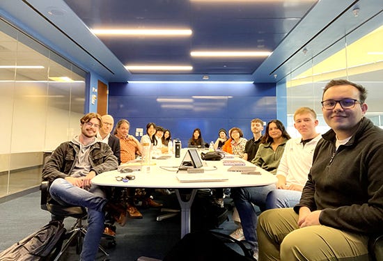 A group of students pose around a long conference table.