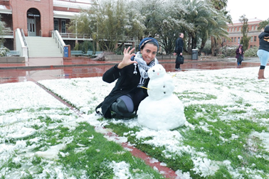 Woman posing with small snowman.
