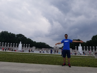 Man posing in front of a monument with a pond.