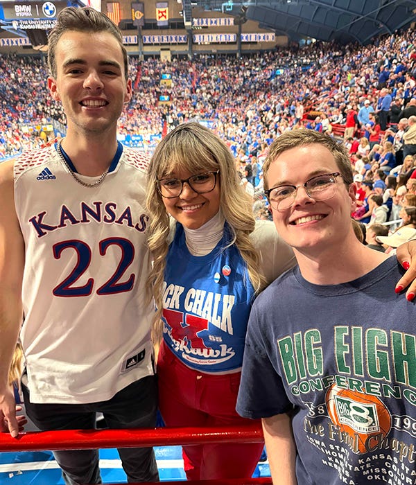 A group poses for a photo at a sporting event wearing KU sportswear.
