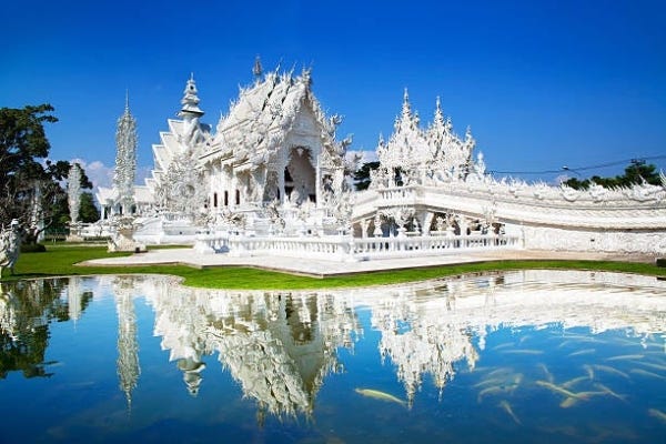 a white temple with a pond in Chiang Rai