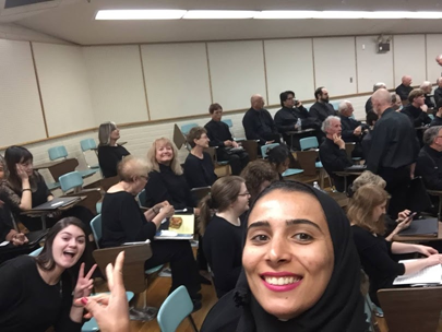 Woman taking a selfie with people sitting at desks.