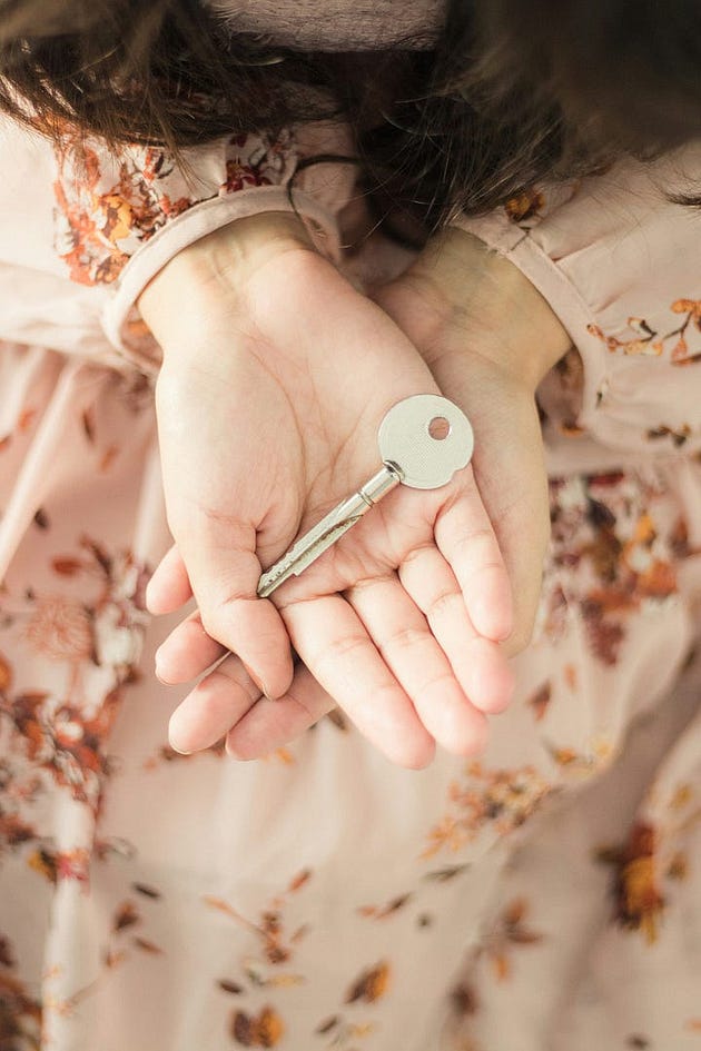 Photo by Fa Barboza on Unsplash of a woman holding a house key.