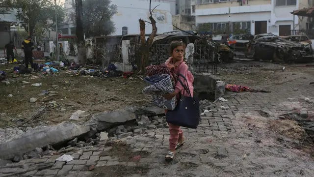 Seorang gadis membawa selimut saat berjalan melewati lokasi ledakan mematikan di Rumah Sakit al-Ahli, Kota Gaza, Rabu (18/10/2023).