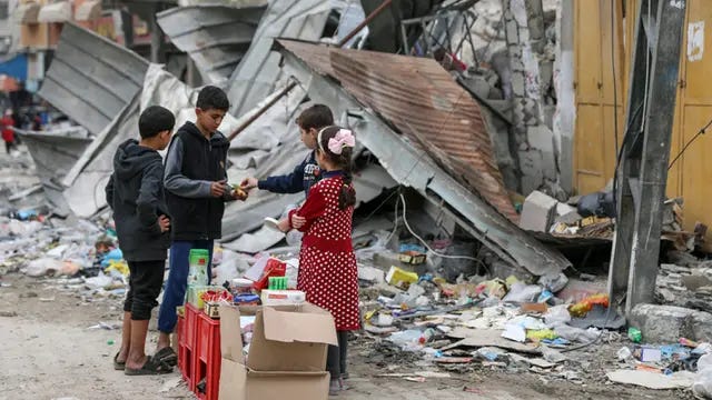 Anak-anak Palestina berjualan manisan pada hari kelima gencatan senjata sementara antara Hamas dan Israel di depan reruntuhan bangunan kamp pengungsi Jebaliya, Jalur Gaza, 28 November 2023.