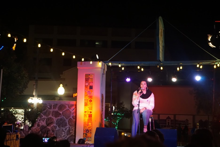 Woman singing on a stage at night.