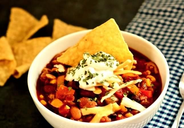 This flavorful one-pot chicken thigh chili is great for lunch or dinner because it combines tender chicken chunks with three different kinds of beans, bell peppers, and tomatoes.
