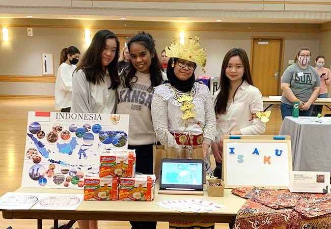 A group of students pose behind a table with information about Indonesia.