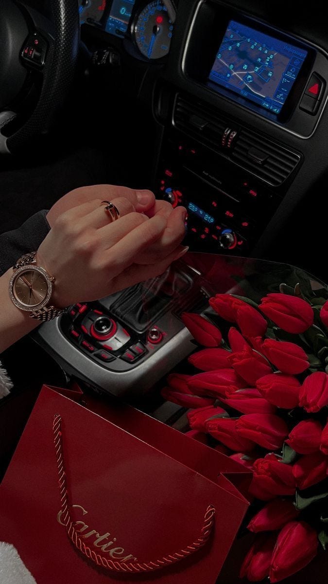 Luxury Valentine’s Day moment featuring a Cartier shopping bag, red roses, and a ring held inside a car, reflecting how high-end jewelry brands associate love with gifting.
