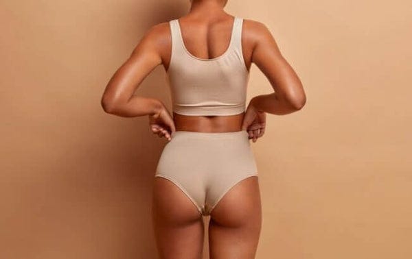 Cropped view of a woman in beige underwear laying her hands on her