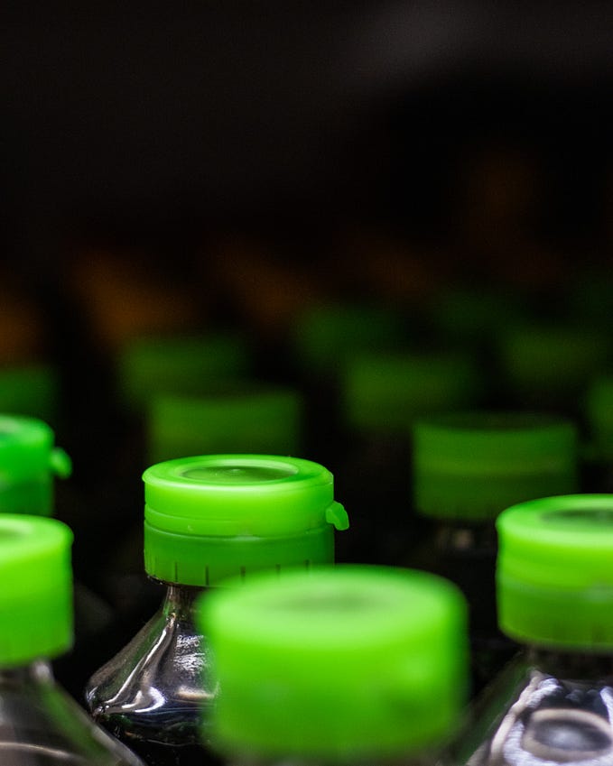A group of plastic bottles, focusing on their bright green plastic caps.