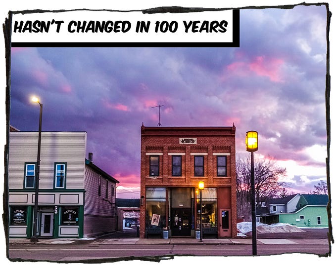 A photo of a small town street at dusk. There are purple and red clouds in the background. The caption reads, “Hasn’t changed in 100 years.”