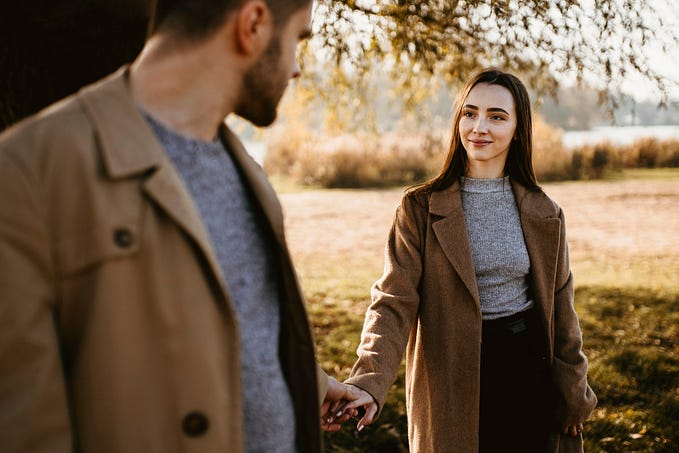 Woman being led by her husband through a park