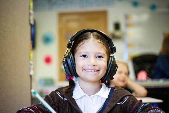 Smiling little girl with a ponytail and big earphones on.