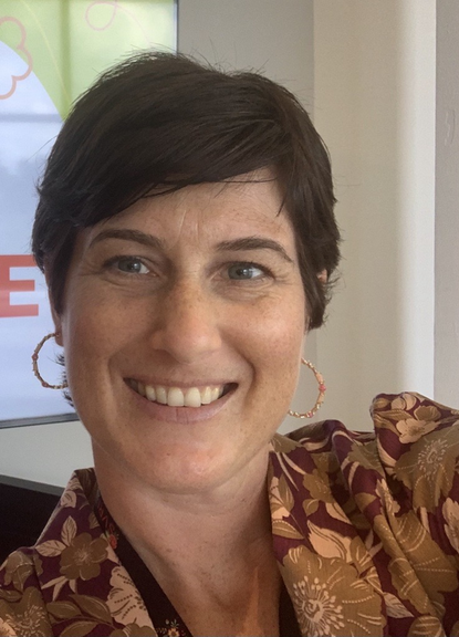 Portrait photo of Abigail Erickson, new Chief of the UN Trust Fund. She is smiling, has white skin, dark brown short hair and little hoop earrings.