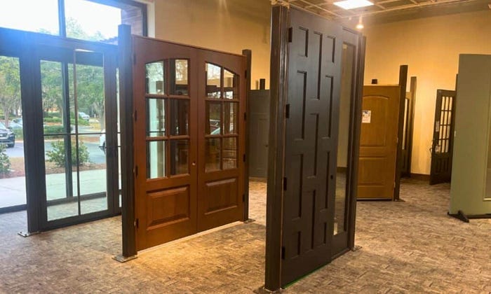 A showroom displaying several doors alongside a large window, showcasing various door designs and styles.