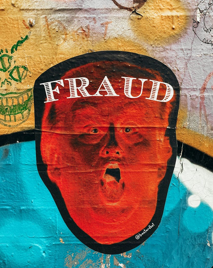 Image of a face drawn on a wall with its mouth open and the word ‘Fraud’ written boldly on the forehead