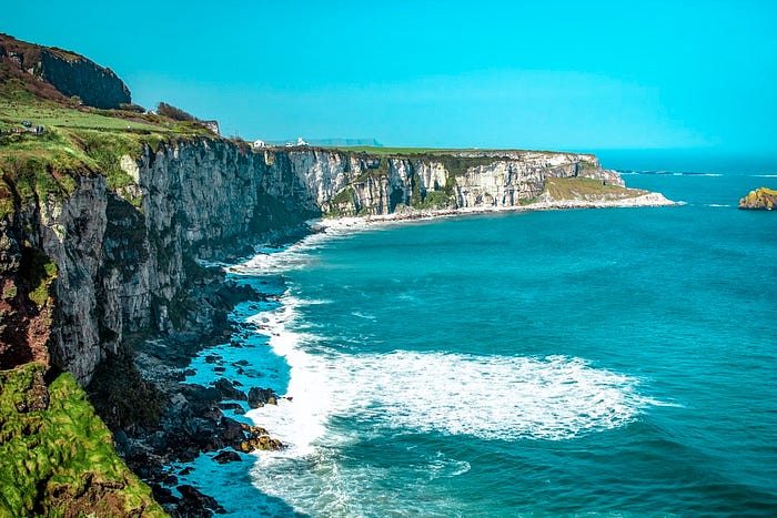 Picture of a cliff by the sea with Rope Bridge, Ireland in the background