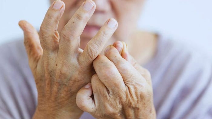 An older woman holds her face in her hands, expressing emotional distress, possibly linked to chronic pain or rheumatoid arthritis.