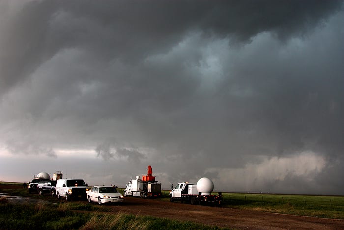 cars on a dirt road with gray clouds overhead