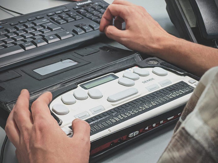 A close up of hands using a keyboard assistive device.