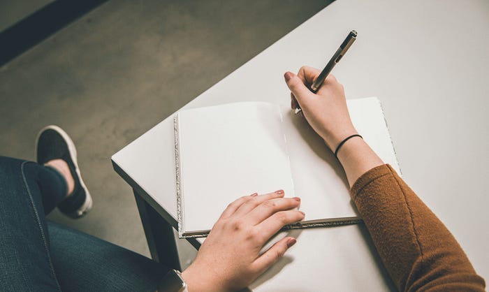 A woman writing on a blank page of a book