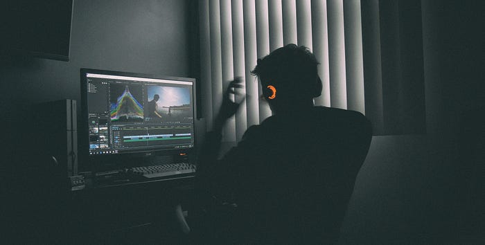 A silhouette of a video editor working on a computer.