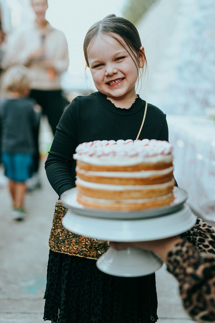 A little girl holding a cake, smiling