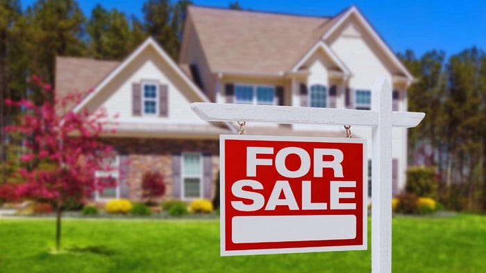 Red and white ‘For Sale’ sign in front of a two-story suburban home with manicured lawn, highlighting houses for sale.
