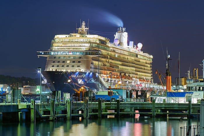 Nighttime picture of A cruise ship in port, burning its fuel to keep the lights on.