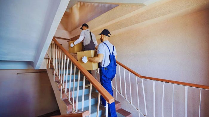 Two professional movers carrying cardboard boxes up a staircase, symbolizing Hilton Head relocation services in Hilton Head Island, SC.