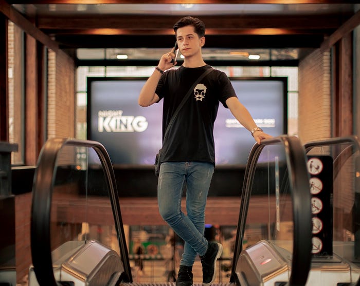 Man in a black shirt on the phone at the top of an elevator