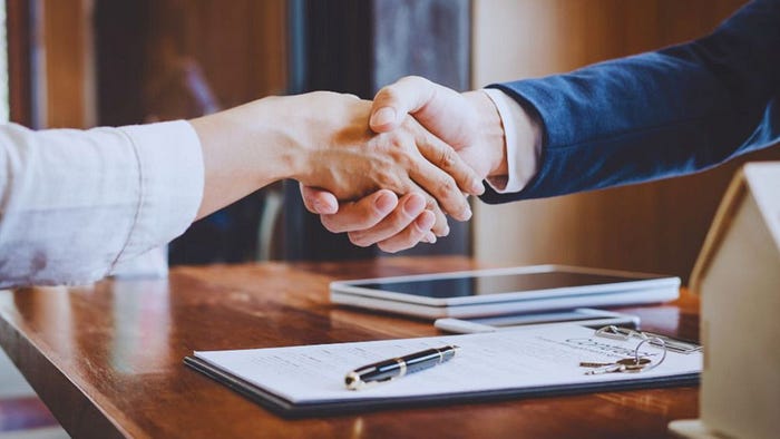Real estate agent in Hilton Head shaking hands with a client over signed property documents, symbolizing a successful home purchase agreement.