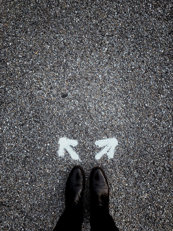 black boots on gray cement with arrows going left and right diagonal