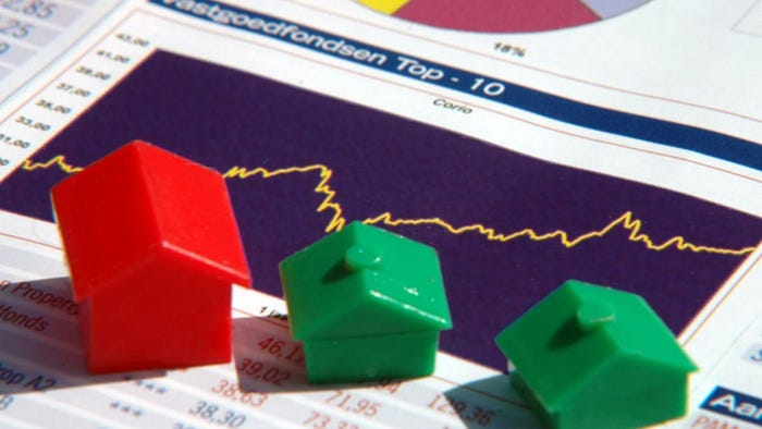 Plastic house models sit atop a property report, illustrating research into local neighborhoods and agents.