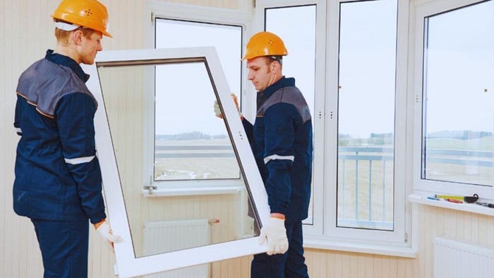Two technicians carrying a large replacement window inside a home during a Bluffton window installation project, preparing to install the new energy-efficient window.