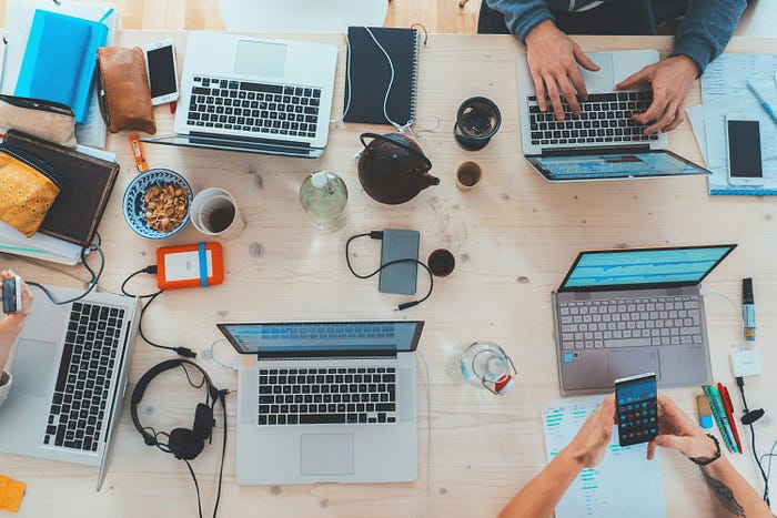 An overhead shot of a table with multiple work laptops.