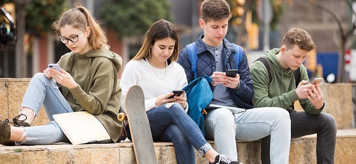 Group of teenagers on their phones — Photographer Unknown