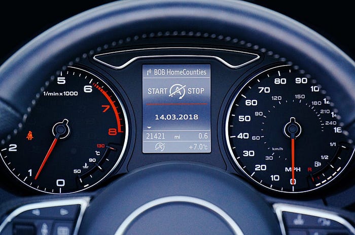 A close-up interior shot of a car, partially showing the steering wheel and buttons