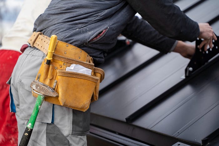 Man working on a roof, performing essential residential roof repairs.