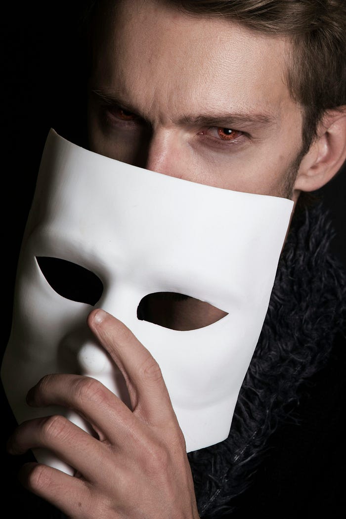 Image of a man holding a white mask, covering part of his face