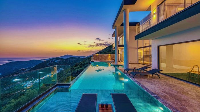 Luxury home in Hilton Head featuring a modern oceanfront design with an infinity pool, glass railings, and panoramic coastal views at sunset.