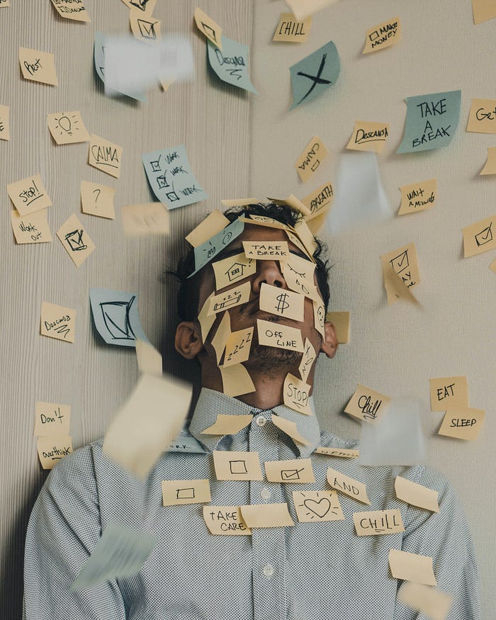 Yellow and blue post-it notes cover a wall and a man wearing a green dotted Oxford shirt 