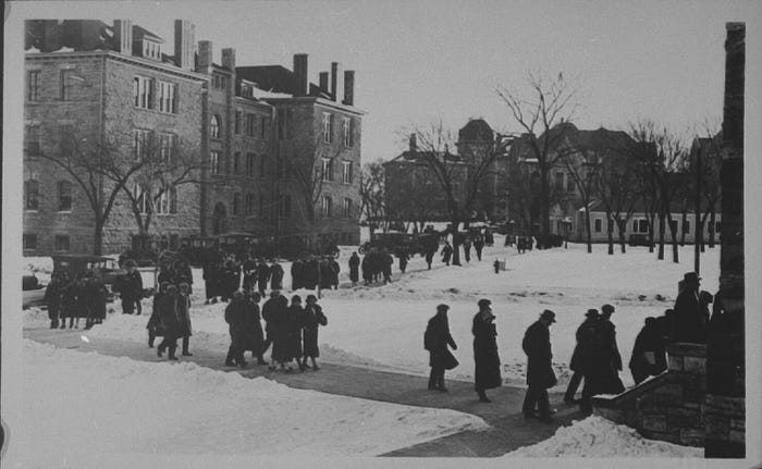 A black and white photo of students walking to and from class in the snow on Jayhawk Boulevard.