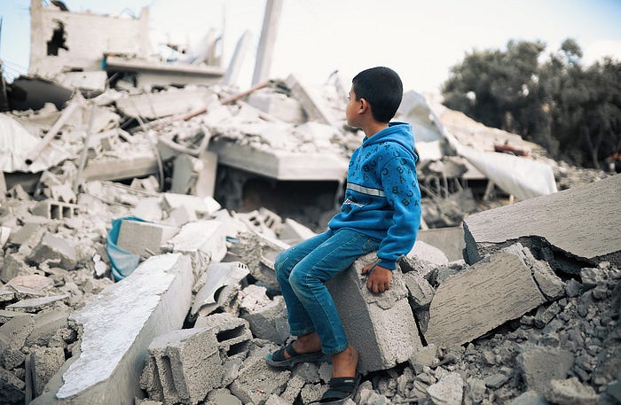 A child sitting in the ruins of a building